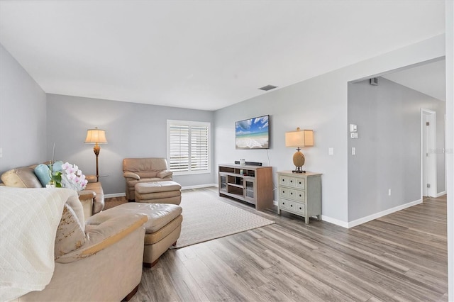 living area featuring visible vents, baseboards, and wood finished floors