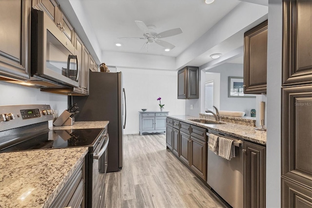 kitchen featuring appliances with stainless steel finishes, a sink, light wood-style flooring, and dark brown cabinetry