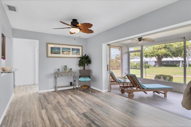 living area featuring a ceiling fan, baseboards, visible vents, and wood finished floors