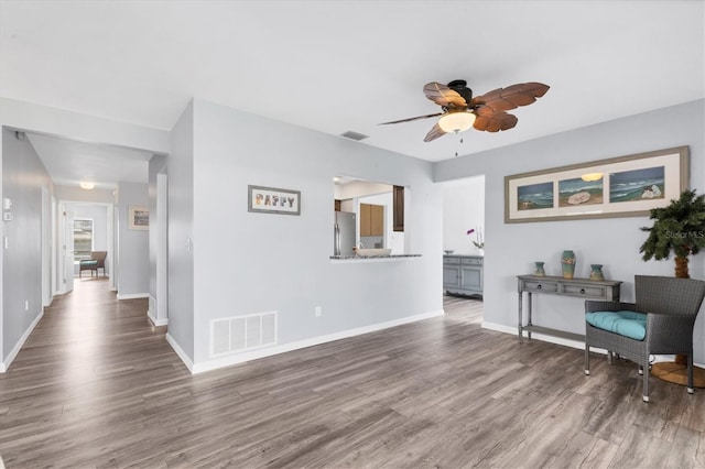 sitting room featuring ceiling fan, wood finished floors, visible vents, and baseboards