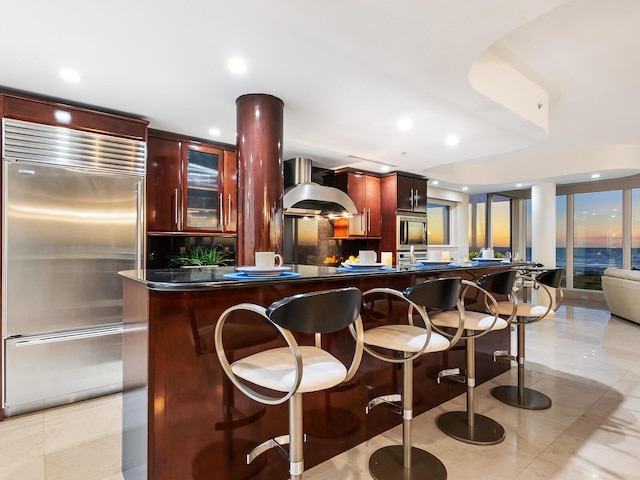 534 Beach Rd, Sarasota, FL 34242 - kitchen featuring a breakfast bar area, exhaust hood, built in fridge, and dark brown cabinets