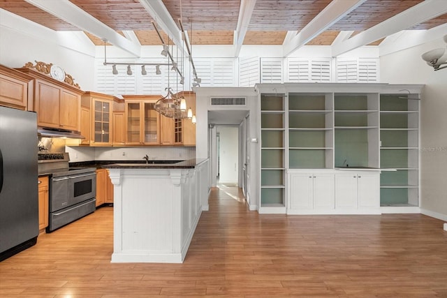 kitchen featuring stainless steel appliances, dark countertops, light wood-style floors, beamed ceiling, and under cabinet range hood