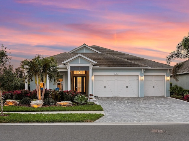 view of front of property featuring decorative driveway, a garage, and a tiled roof