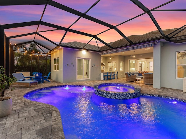 pool at dusk with outdoor lounge area, a patio area, a pool with connected hot tub, and ceiling fan