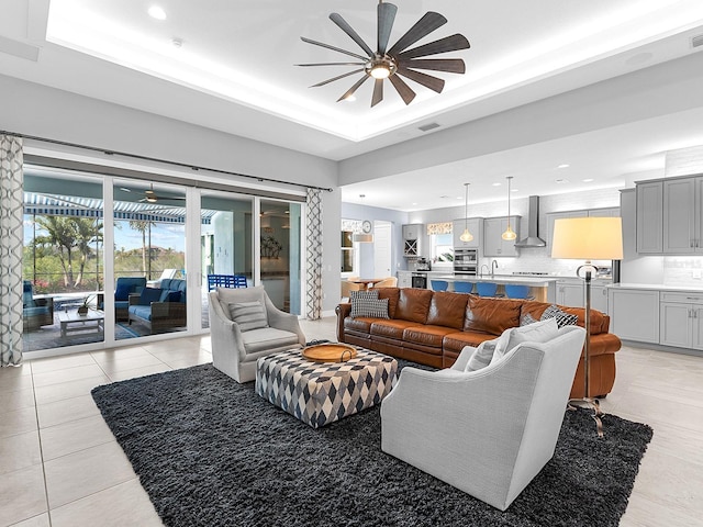 living room with visible vents, light tile patterned flooring, recessed lighting, ceiling fan, and a raised ceiling