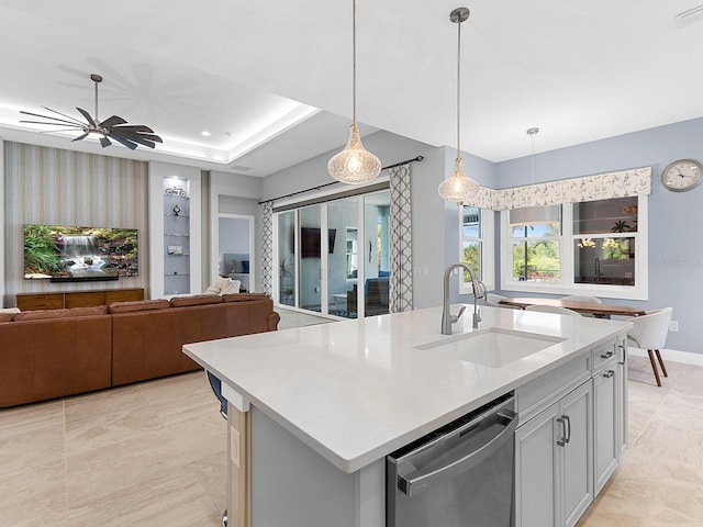 kitchen with an island with sink, a sink, open floor plan, light countertops, and dishwasher