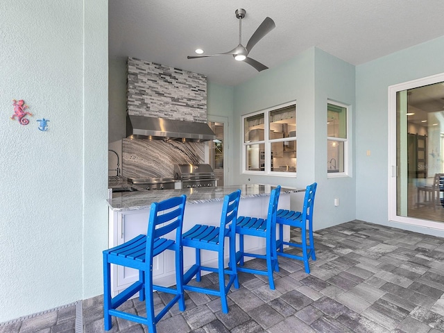 view of patio / terrace featuring grilling area, outdoor wet bar, exterior kitchen, and a ceiling fan