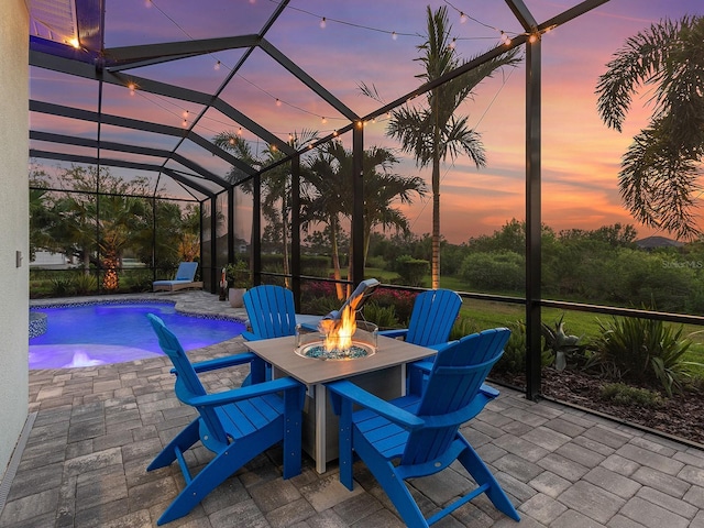 patio terrace at dusk featuring an outdoor pool, a fire pit, and a lanai