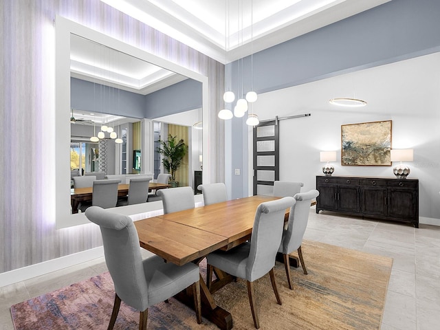 dining room featuring light tile patterned flooring, baseboards, a barn door, and a towering ceiling