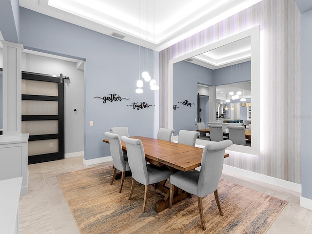 tiled dining area with a barn door, baseboards, visible vents, and a tray ceiling