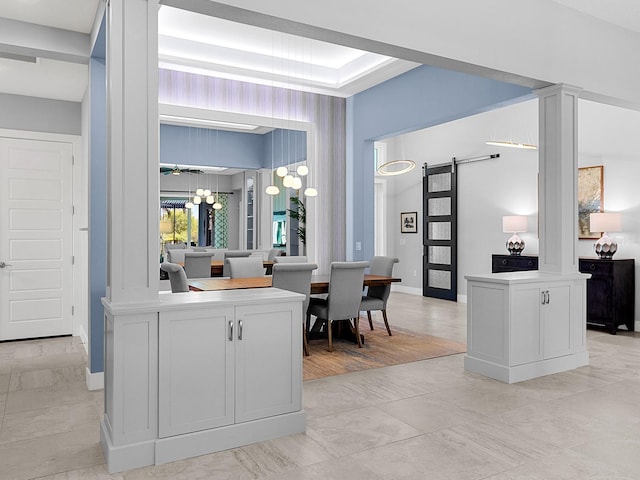 kitchen featuring a barn door, light countertops, baseboards, and ornate columns