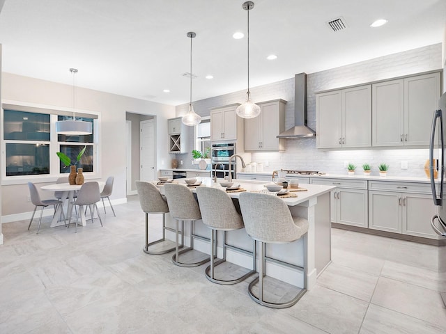 813 Tailwind Pl, Sarasota, FL 34240 - kitchen with wall chimney range hood, gray cabinets, light countertops, tasteful backsplash, and a breakfast bar
