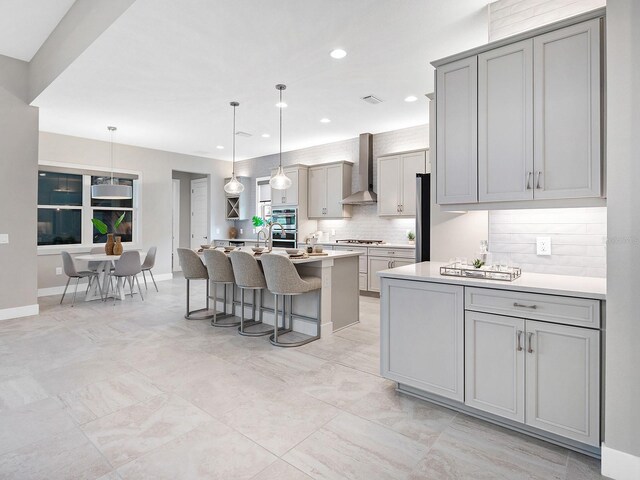 813 Tailwind Pl, Sarasota, FL 34240 - kitchen with wall chimney range hood, gray cabinetry, backsplash, a kitchen breakfast bar, and recessed lighting