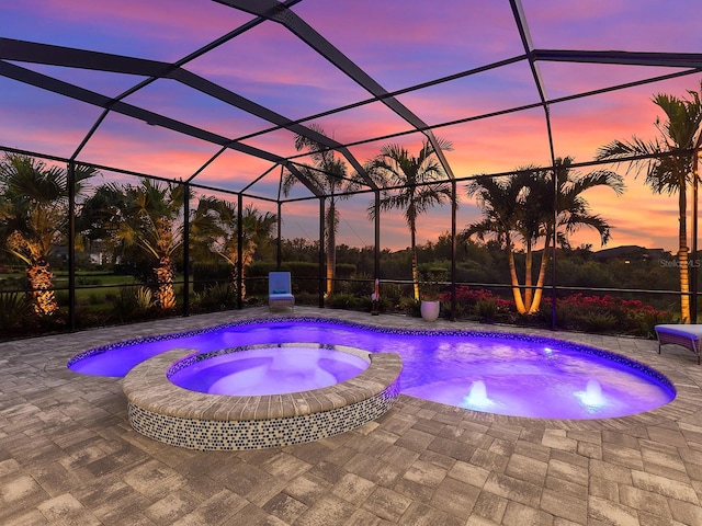 813 Tailwind Pl, Sarasota, FL 34240 - pool at dusk featuring a pool with connected hot tub, a patio, and a lanai