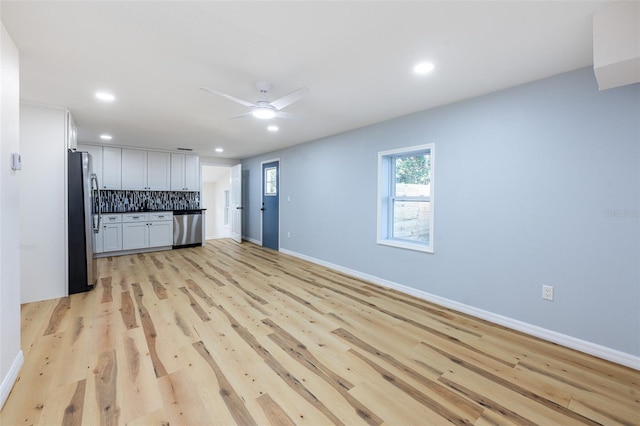 kitchen with baseboards, light wood finished floors, recessed lighting, appliances with stainless steel finishes, and backsplash