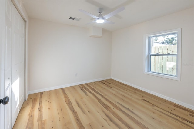 empty room with light wood-type flooring, visible vents, baseboards, and ceiling fan