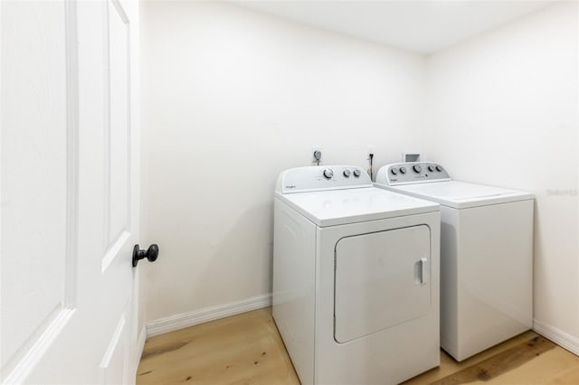 washroom featuring baseboards, light wood-style floors, laundry area, and washing machine and clothes dryer