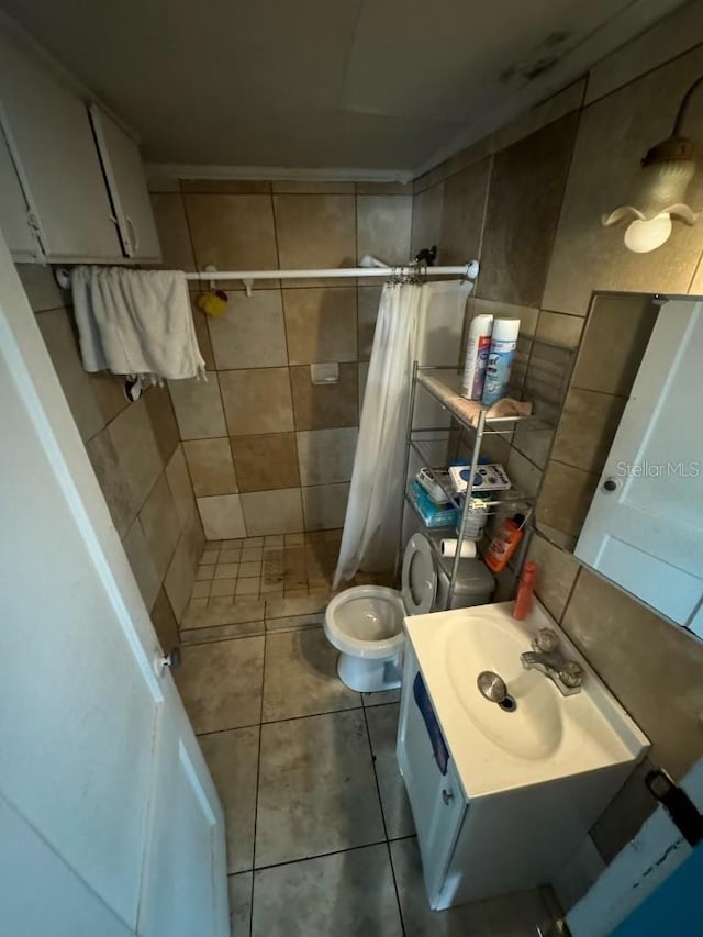 full bathroom with toilet, vanity, a stall shower, tile patterned floors, and tile walls