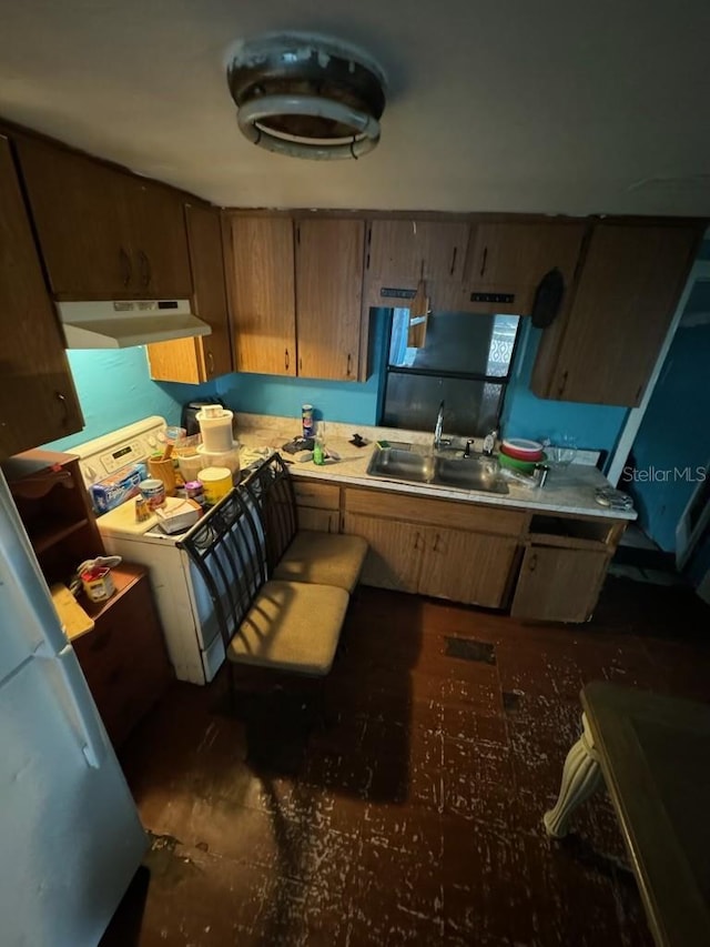 kitchen with under cabinet range hood, range, light countertops, and a sink