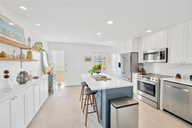 kitchen with light tile patterned flooring, stainless steel appliances, a kitchen island, white cabinets, and open shelves