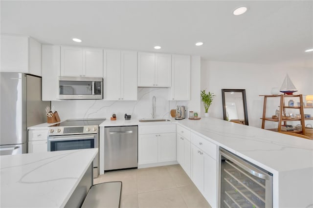 kitchen featuring wine cooler, light tile patterned flooring, a peninsula, a sink, and appliances with stainless steel finishes