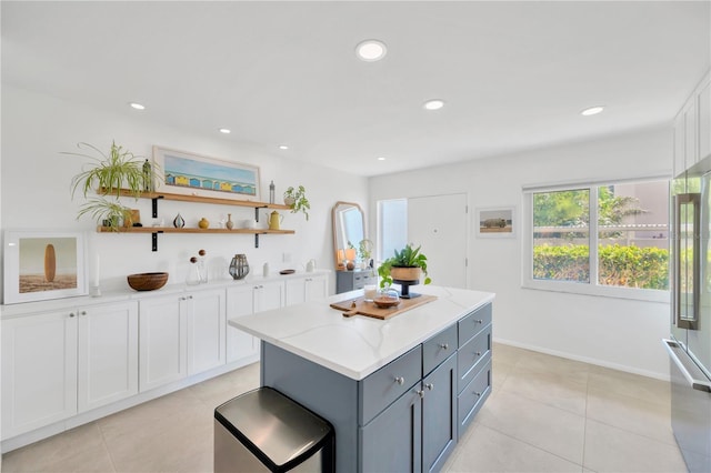 kitchen with light tile patterned floors, light stone counters, white cabinetry, gray cabinets, and a center island