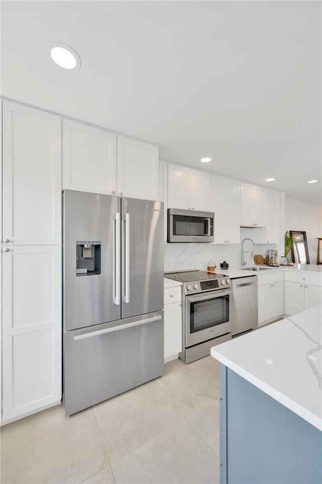 kitchen with light tile patterned floors, recessed lighting, appliances with stainless steel finishes, white cabinetry, and a sink