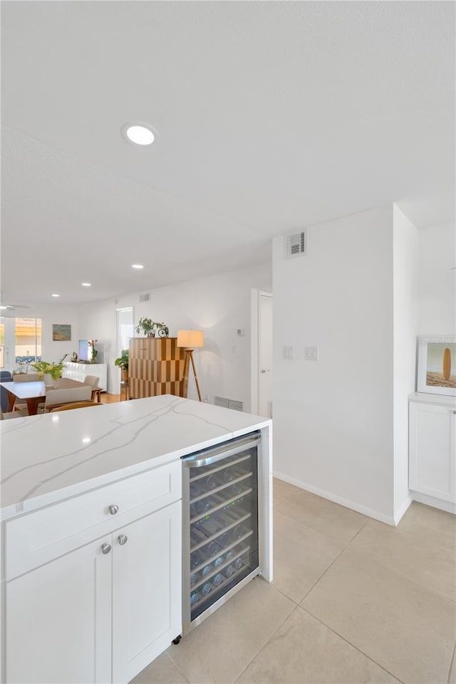 kitchen with wine cooler, visible vents, white cabinetry, open floor plan, and light stone countertops