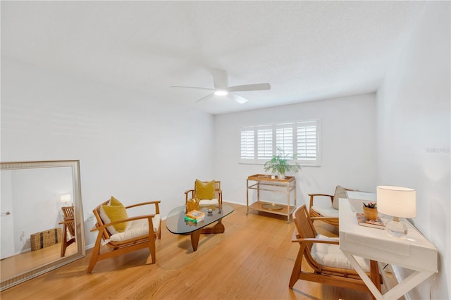 sitting room featuring light wood-style flooring, baseboards, and a ceiling fan