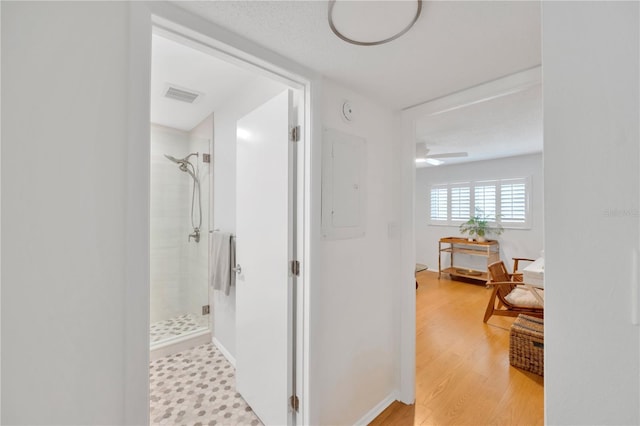 bathroom with visible vents, a stall shower, wood finished floors, electric panel, and baseboards