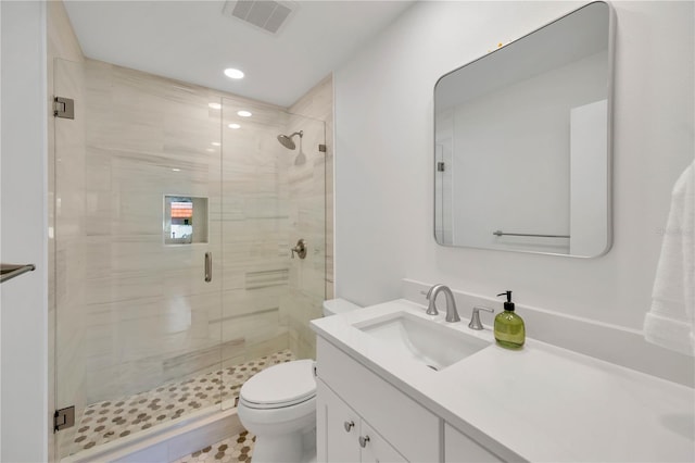 full bathroom with toilet, vanity, a shower stall, and visible vents