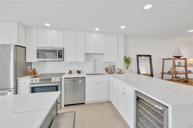 1600 1st Ave W Unit 102A, Bradenton, FL 34205 - kitchen with stainless steel appliances, a sink, a peninsula, wine cooler, and light tile patterned flooring