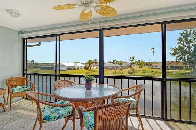 sunroom with a water view and ceiling fan