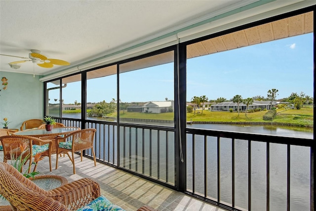 sunroom / solarium featuring a ceiling fan and a water view