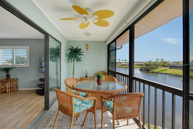 sunroom / solarium with a water view and a ceiling fan