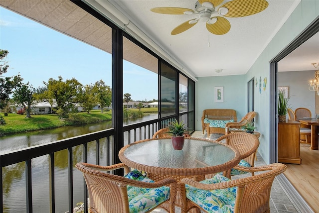 balcony with a sunroom, a water view, and ceiling fan