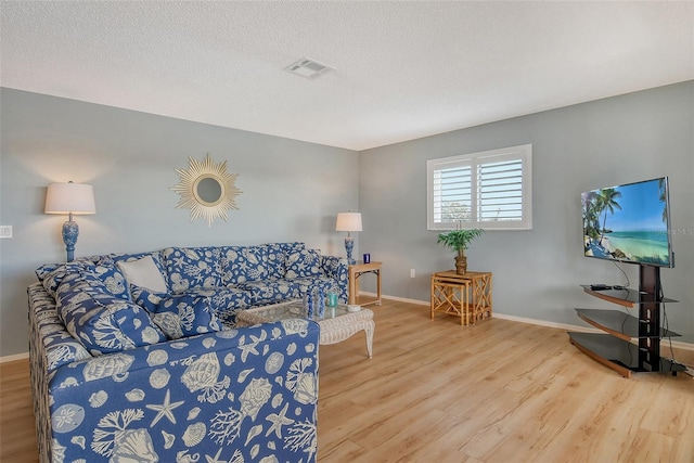 living room featuring a textured ceiling, wood finished floors, and baseboards