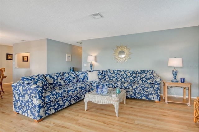 living room with visible vents, a textured ceiling, baseboards, and wood finished floors