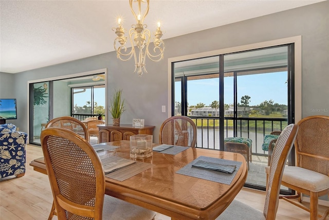 dining room with a textured ceiling, light wood finished floors, and an inviting chandelier