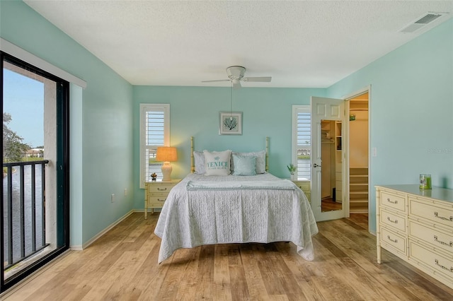 bedroom featuring a textured ceiling, light wood finished floors, visible vents, and baseboards