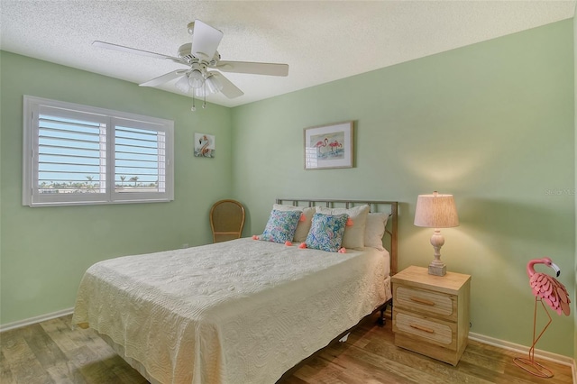 bedroom featuring a textured ceiling, baseboards, and wood finished floors