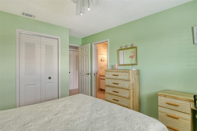 bedroom featuring visible vents, a ceiling fan, ensuite bathroom, a textured ceiling, and a closet