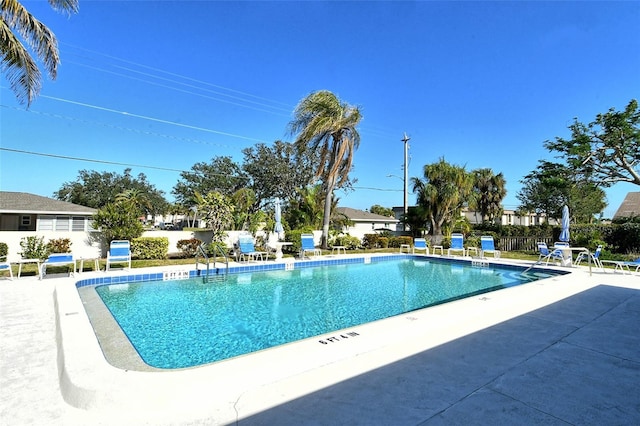 community pool with a patio area and fence