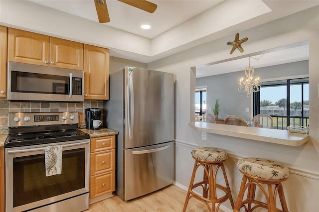 kitchen featuring stainless steel appliances, a wealth of natural light, light wood-style floors, and decorative backsplash