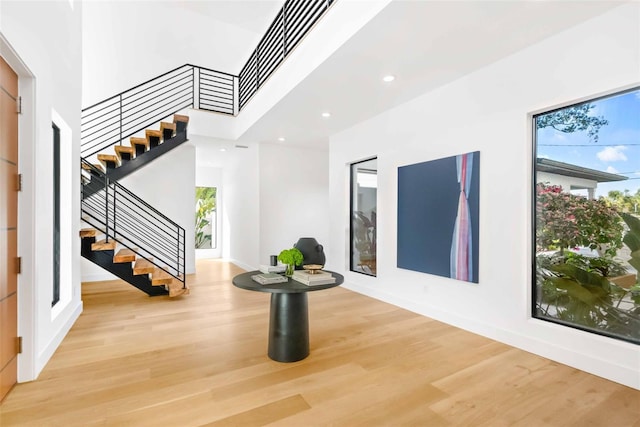 foyer entrance with light wood-type flooring, stairs, a towering ceiling, and recessed lighting