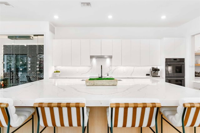 kitchen featuring dobule oven black, a sink, visible vents, and decorative backsplash