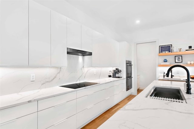 kitchen featuring black appliances, modern cabinets, a sink, and under cabinet range hood