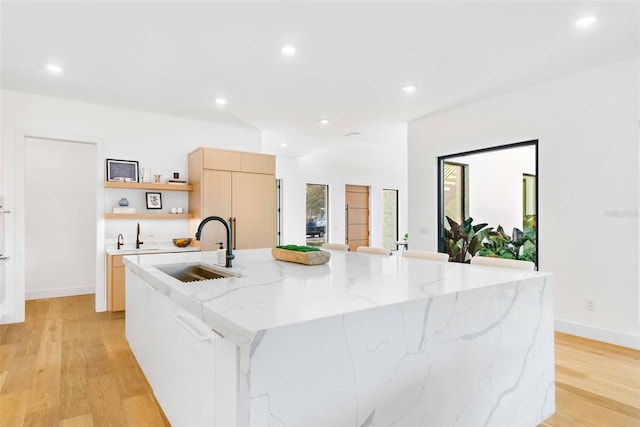 kitchen featuring a large island, modern cabinets, light wood-style flooring, open shelves, and a sink