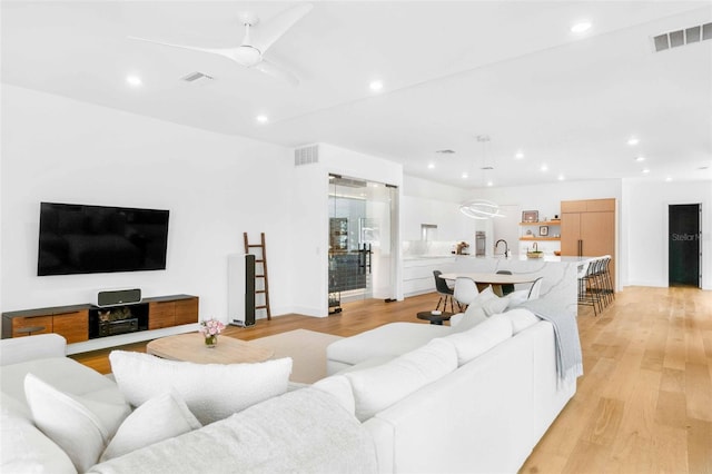 living room with light wood-type flooring, visible vents, and recessed lighting