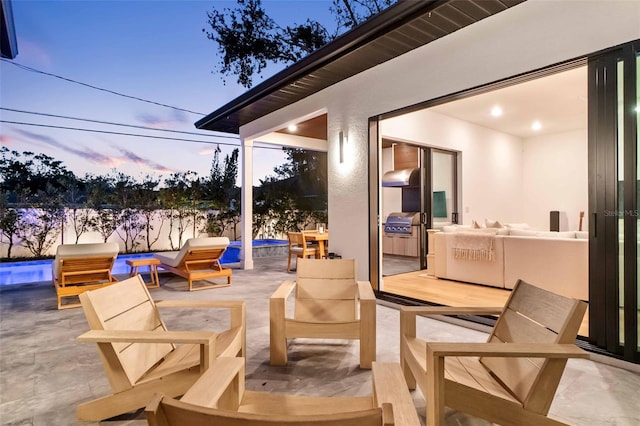 patio terrace at dusk featuring grilling area, outdoor lounge area, and a fenced in pool